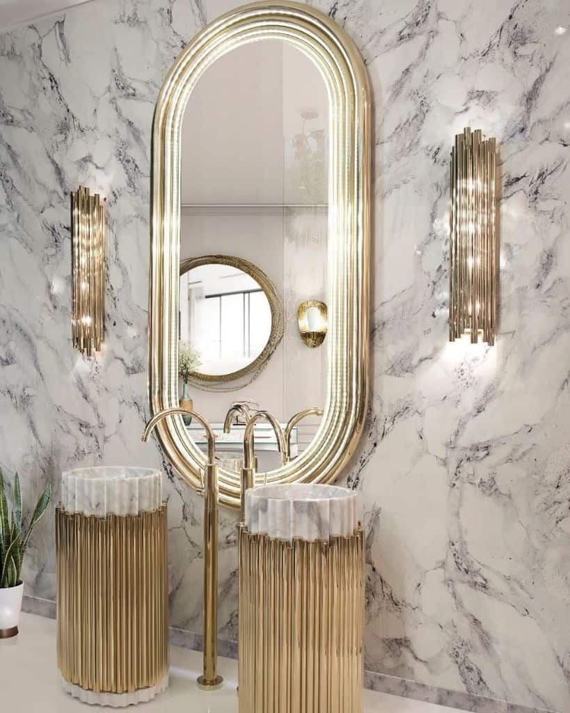 Luxurious bathroom with marble walls, gold-framed mirror, and matching gold sinks and fixtures.