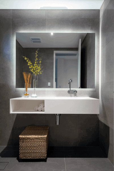 Modern bathroom with LED backlit mirror, floating sink, and woven storage basket.