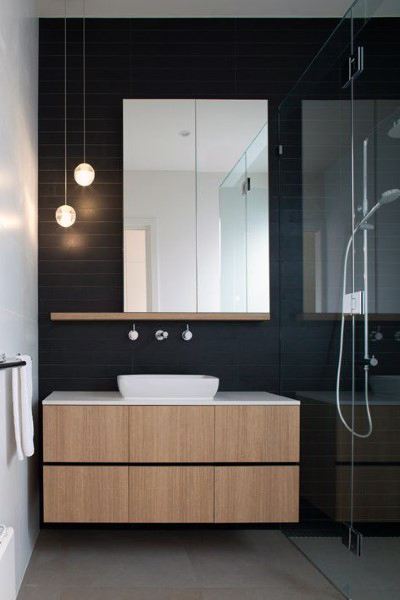 Minimalist bathroom with frameless mirror, wooden vanity, and glass shower enclosure.