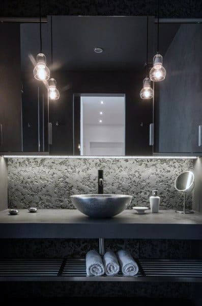Dark modern bathroom with LED backlit mirror, vessel sink, and pendant lighting.