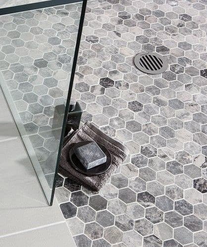 Grey hexagonal tile shower floor with glass partition and central drain.