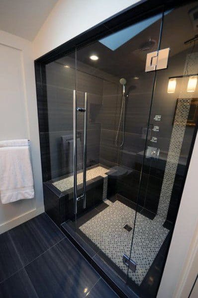 Black porcelain tile shower with mosaic floor, glass enclosure, and built-in bench.
