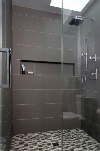 Grey matte ceramic tile shower with mosaic floor, recessed shelf, and glass enclosure.