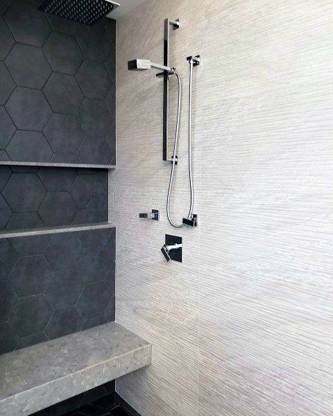 Black hexagonal tile accent wall with modern shower fixtures and built-in bench.