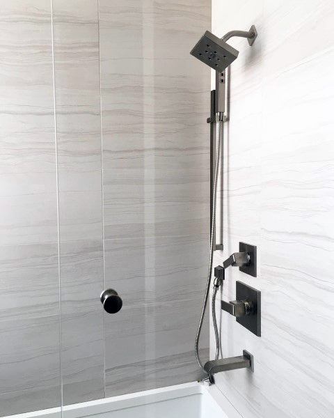 Glossy porcelain tile shower with modern square showerhead and sleek fixtures.