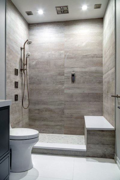 Travertine tile shower with built-in bench, modern fixtures, and adjacent toilet.