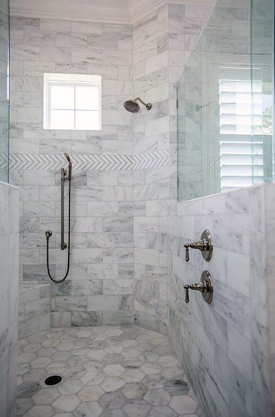 Marble shower with hexagon floor tiles, herringbone accent strip, and handheld showerhead.