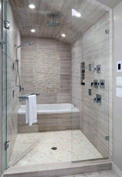 Travertine tile shower with built-in bathtub, mosaic accent wall, and glass enclosure.