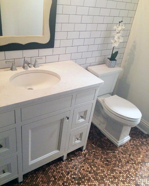 Bathroom with penny tile floor, white vanity, subway tile wall, and decorative orchid plant.