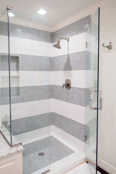 Striped mosaic and white tile shower with glass enclosure and built-in niche.