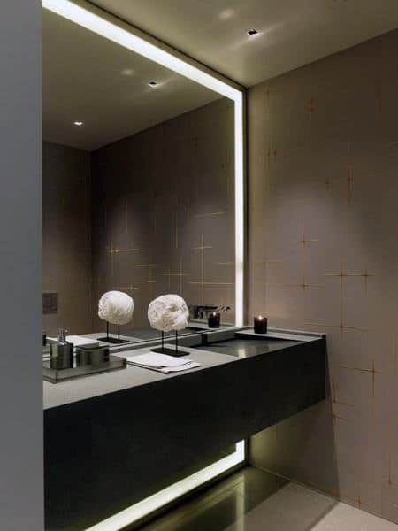 Minimalist bathroom with large LED backlit mirror, sleek vanity, and modern decor accents.