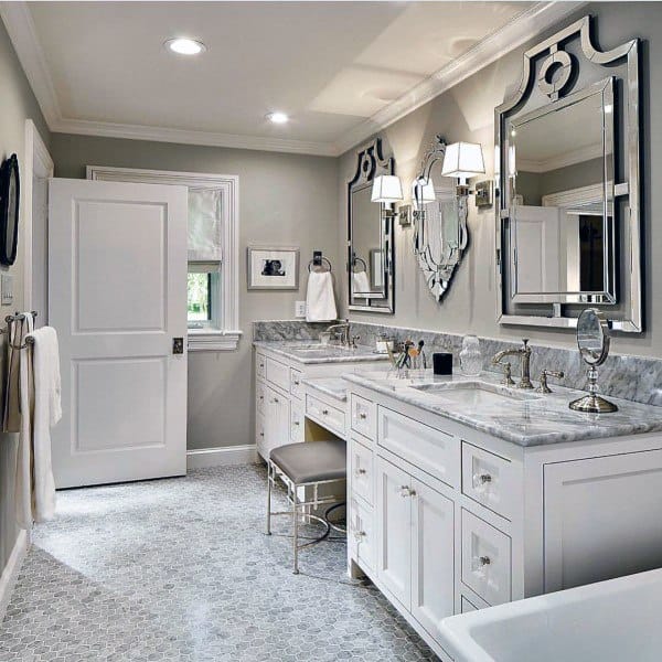 Spacious bathroom with double vanity, metallic-framed mirrors, and marble countertops.