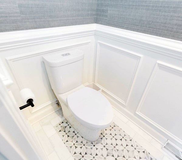 Bright bathroom with white chair rail molding, textured wallpaper, and patterned tile flooring for a refined look
