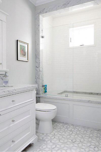 White bathroom with marble accents, subway tile shower, and patterned tile floor.