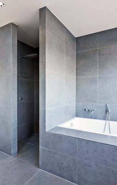 Modern bathroom with large gray concrete tiles and a built-in bathtub.