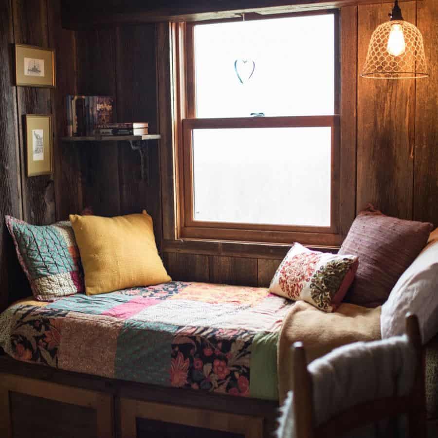 wood panel wall window seat with colorful pillows and rug