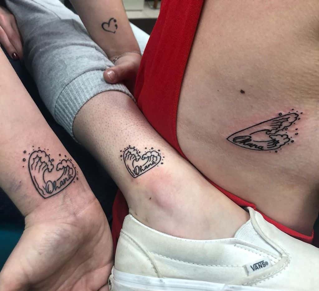 Matching tattoos of hands forming hearts and a wave, with 'Ohana' written, symbolizing family, love, and unity among loved ones.