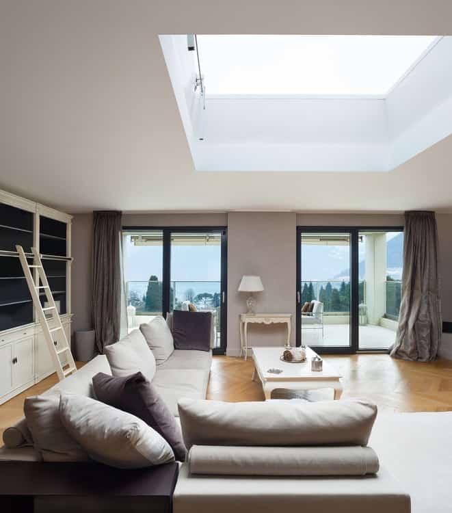 The ceiling features a large skylight that floods the living room with natural light, creating a bright and airy atmosphere in the spacious apartment