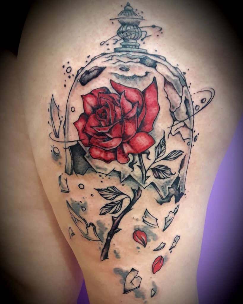Artistic tattoo of the enchanted rose inside a shattered glass dome, featuring bold red petals, black ink shading, and abstract elements.