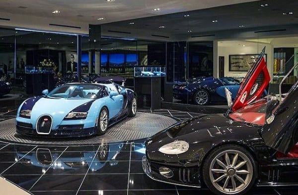 A luxurious home garage featuring a Bugatti Veyron and sleek sports cars, accentuated by polished black tile flooring and mirrored walls.