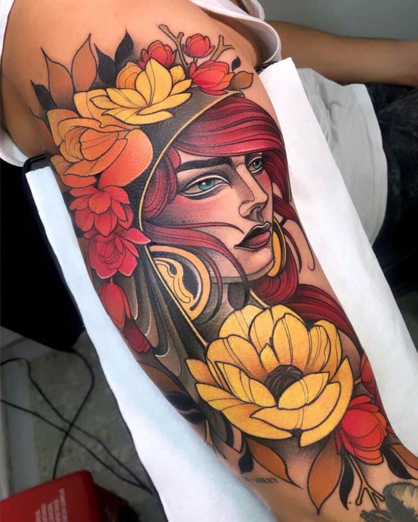 Vibrant full-sleeve tattoo of a gypsy woman with flowing red hair, piercing green eyes, and bold yellow and red floral details.