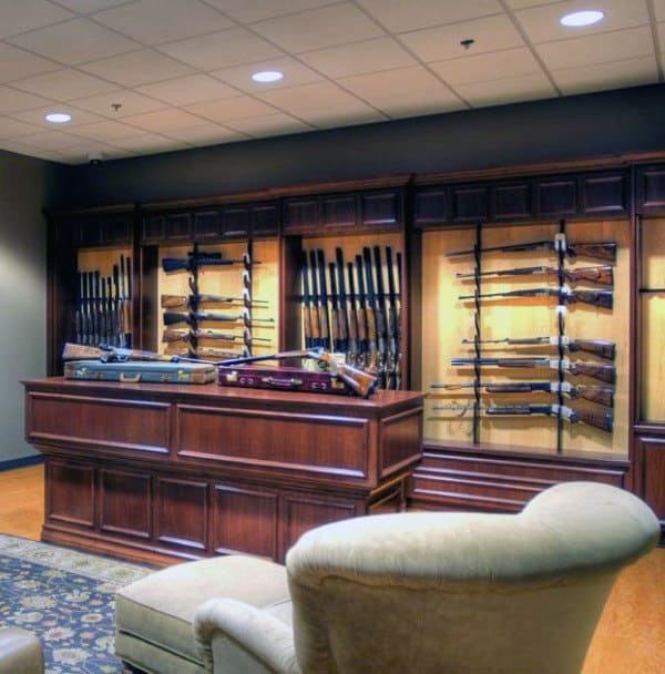 Elegant gun room with wood displays, central counter, and cozy armchair.