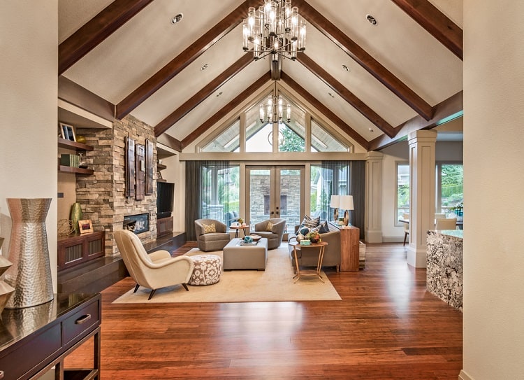 Spacious living room with vaulted ceiling, rustic wooden beams, comfy seating, and expansive windows