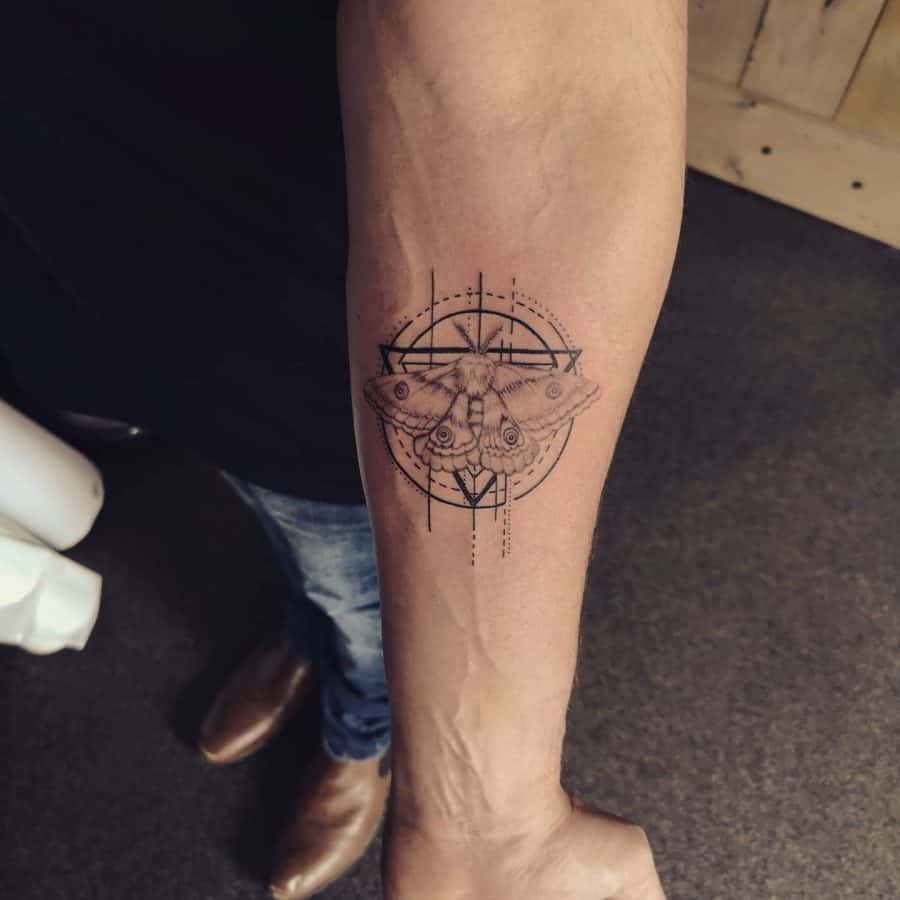 Forearm tattoo with a detailed moth and geometric compass design, combining fine lines and dot work for a bold modern statement.