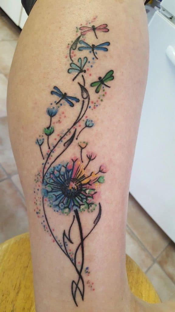 A colorful and detailed tattoo featuring dandelions and butterflies, symbolizing lightness and freedom.