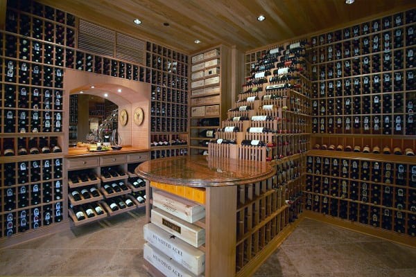 A wine cellar with numerous wine bottles on wooden racks and a central table showcasing more selections
