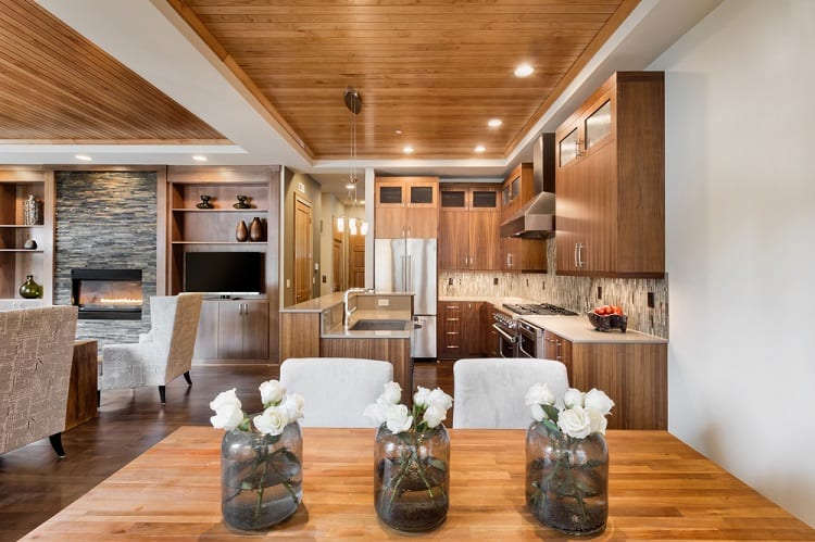 A modern kitchen and dining area featuring a beautiful wooden tray ceiling, sleek cabinetry, and elegant decor, creating a warm, inviting atmosphere