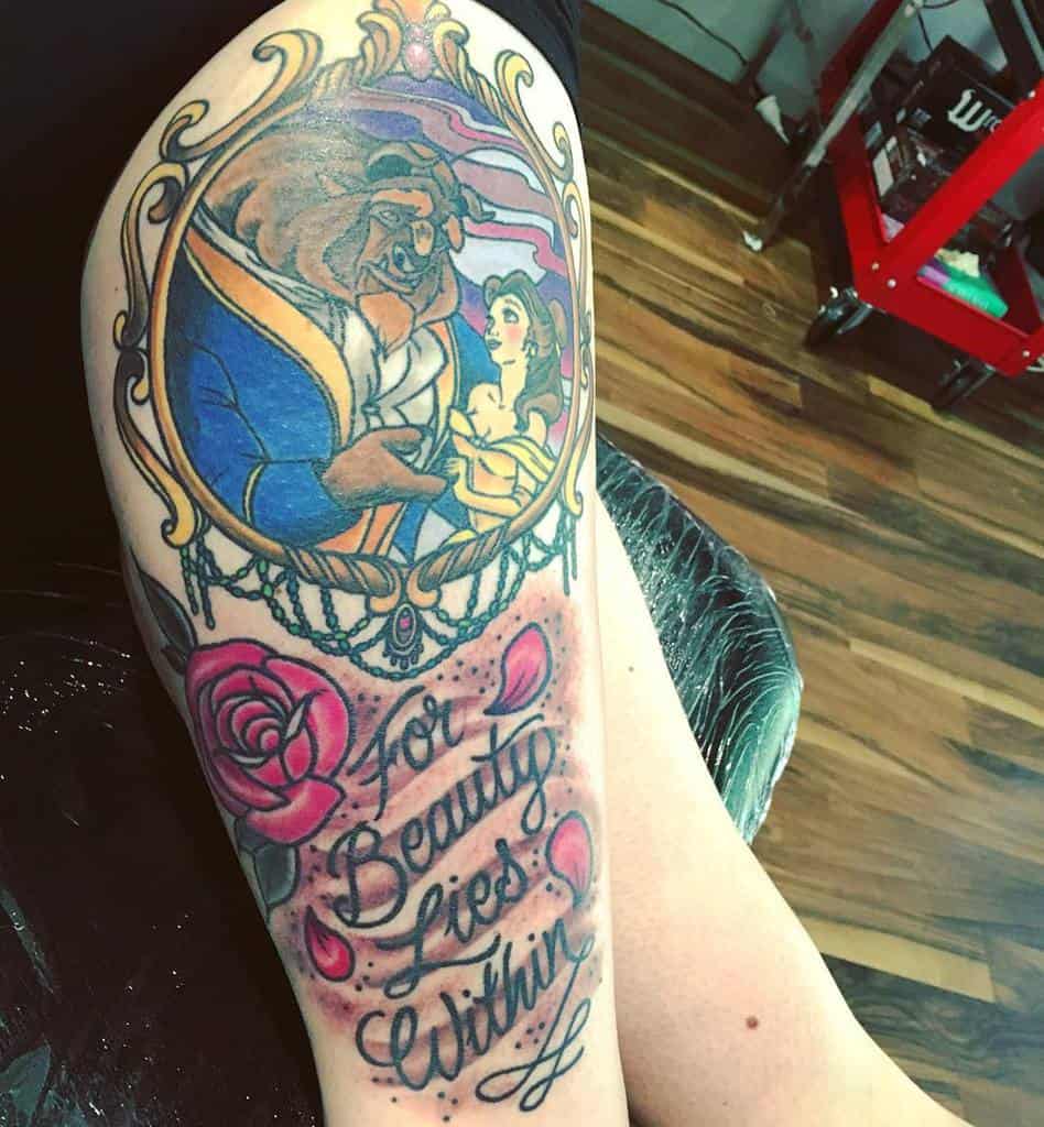 Tattoo featuring Belle and the Beast framed in an ornate mirror, with roses, decorative elements, and the quote 'For Beauty Lies Within'.