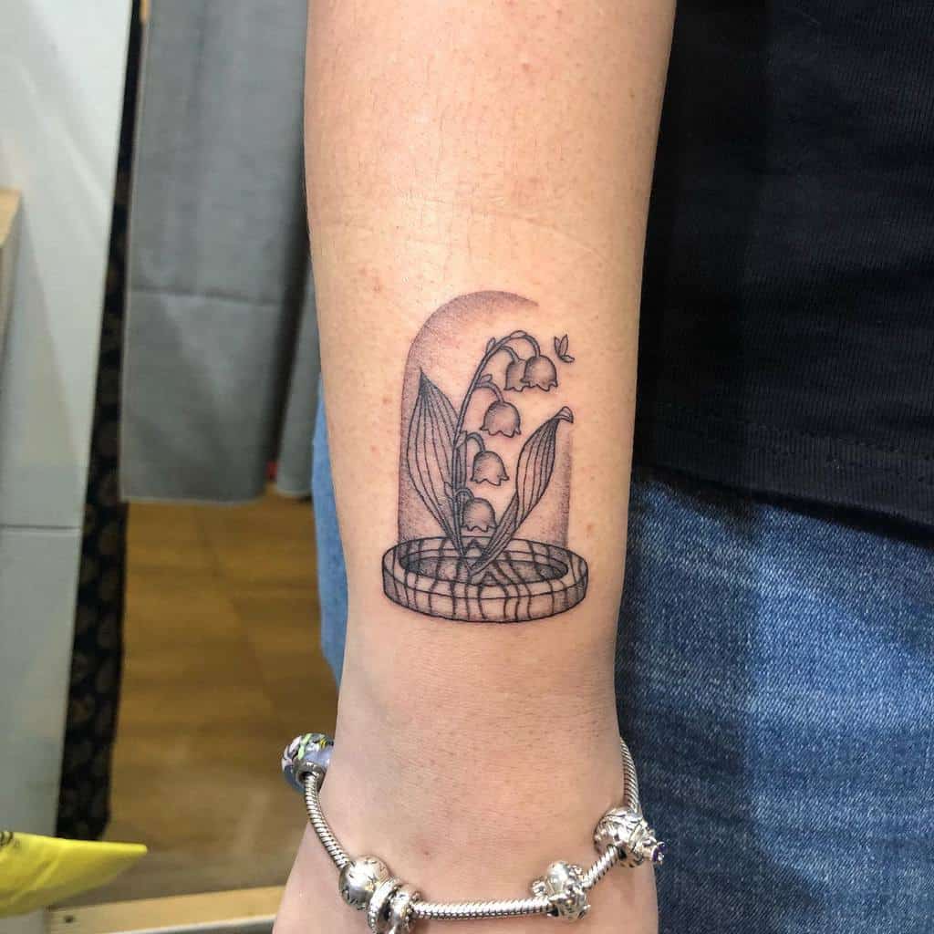 Fine-line Lily of the Valley tattoo, featuring delicate flowers enclosed in a glass dome, butterfly