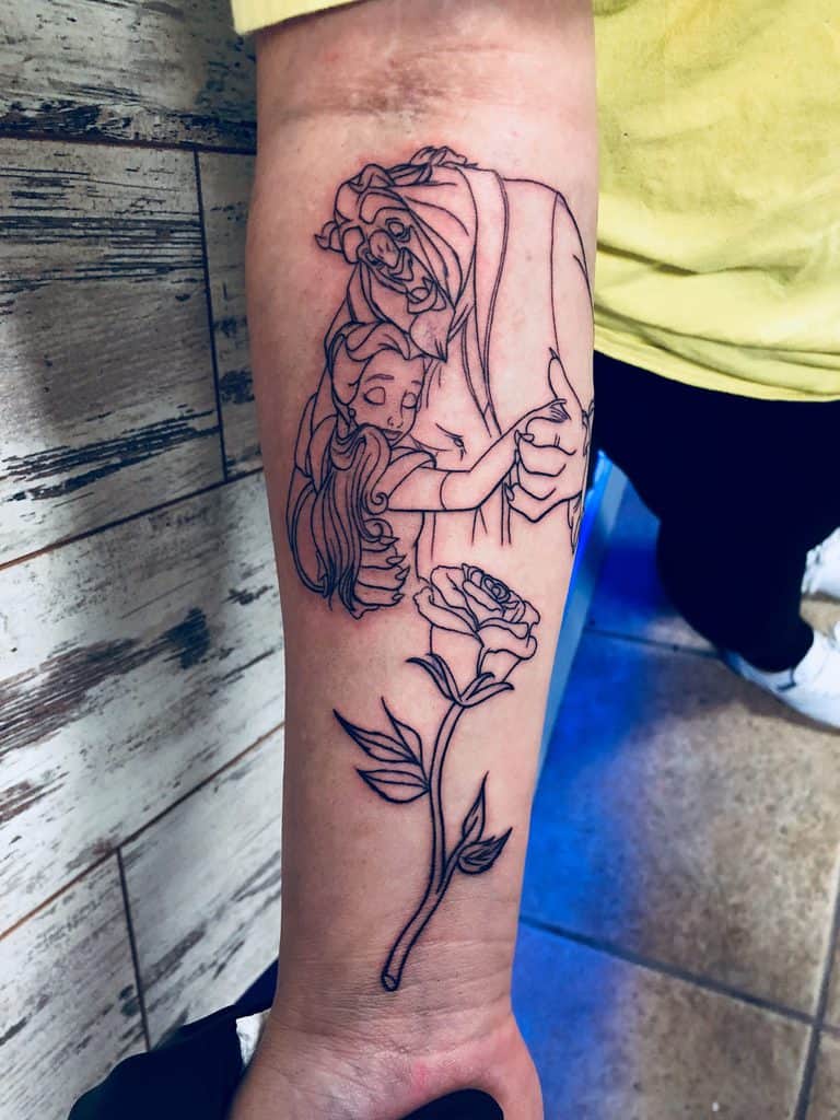 Fine-line forearm tattoo of Belle and the Beast embracing, with a delicate enchanted rose below, symbolizing love and transformation.
