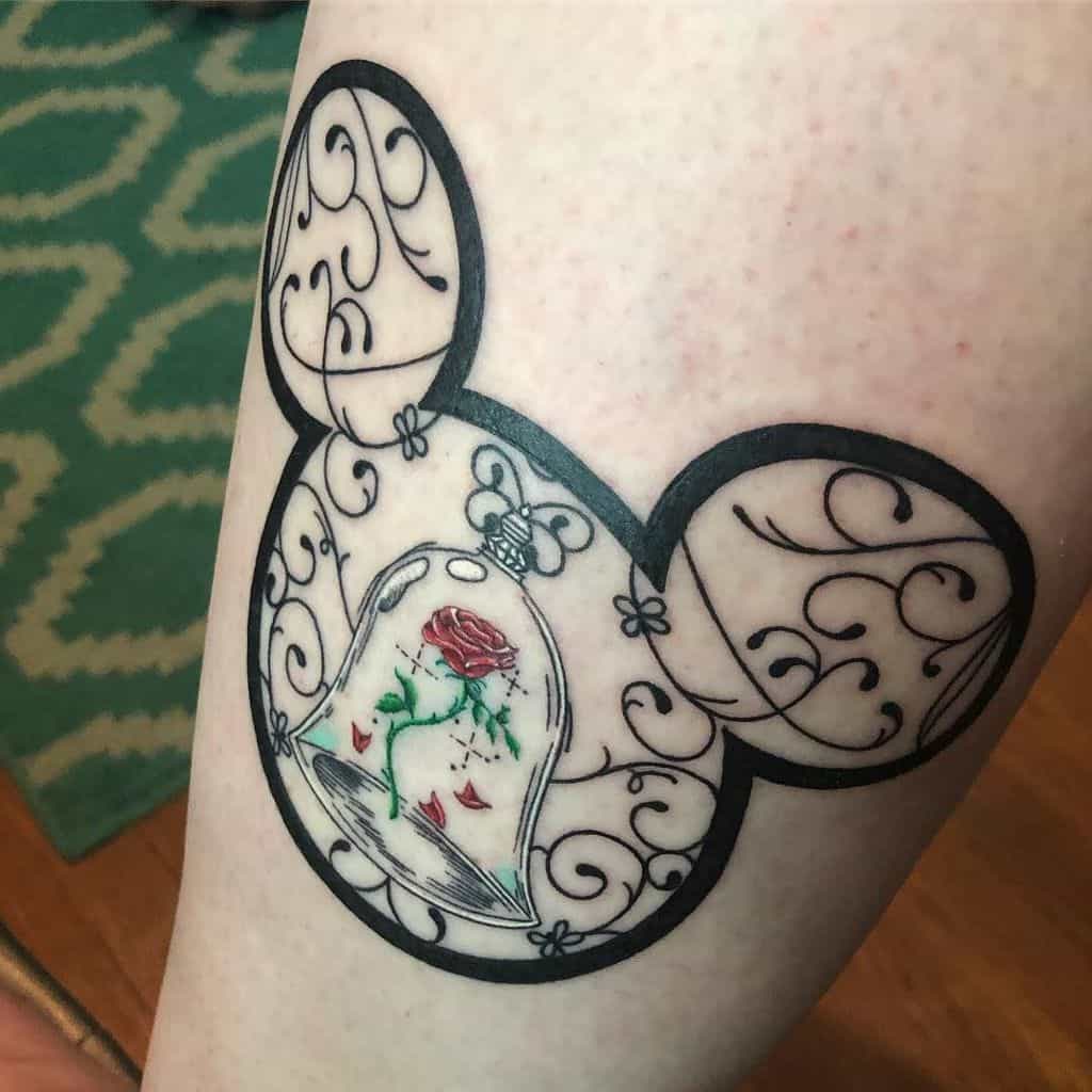 Elegant tattoo of the enchanted rose inside a glass dome, set within a Mickey Mouse silhouette with intricate swirling patterns.