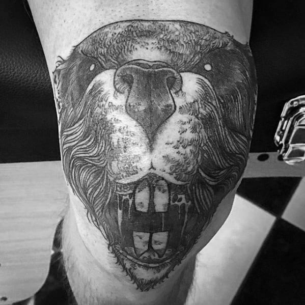 Black and grey beaver tattoo with intense shading, focusing on the face and large teeth, positioned on the knee for dramatic impact.