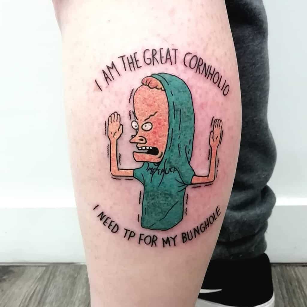 A colorful tattoo of a cartoon character in a green hoodie with arms raised, surrounded by the text 'I am the Great Cornholio' and 'I need TP for my bunghole.'