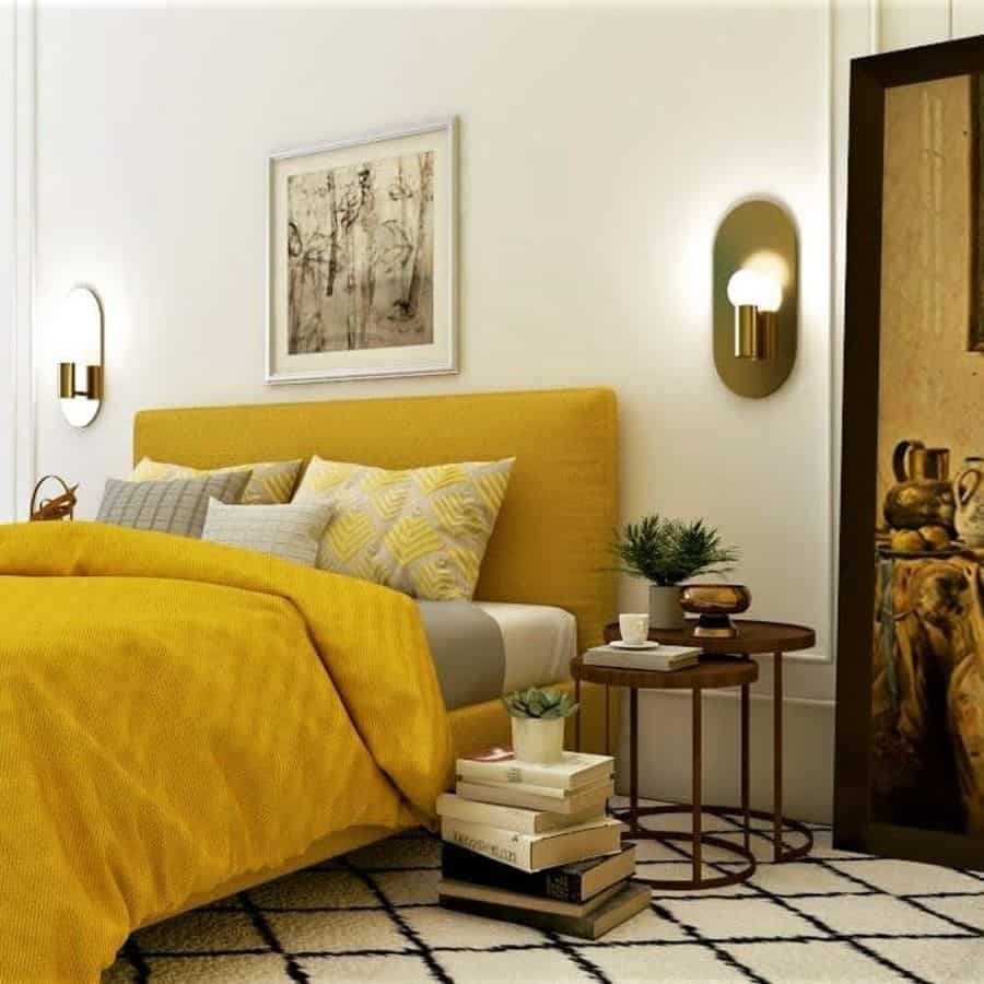 A cozy bedroom featuring a mustard yellow bedspread, decorative pillows, sleek side tables, and modern wall sconces