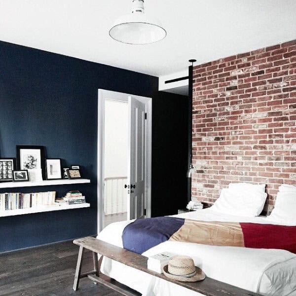 Modern bedroom with brick wall, blue accent wall, and a colorful bedspread
