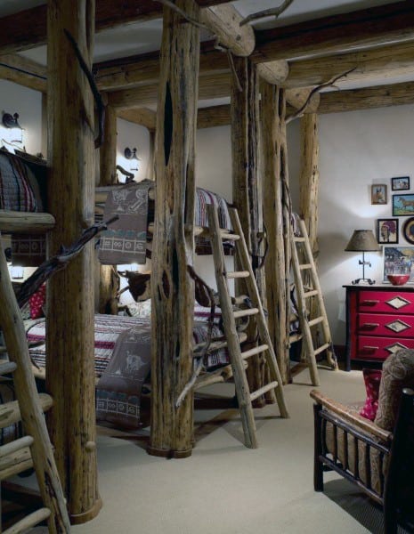 Rustic bedroom with bunk beds, ladders, and a red dresser for a cozy cabin atmosphere