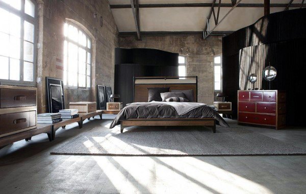 Industrial bedroom with exposed beams, large windows, and wooden furniture.