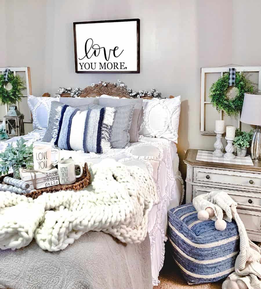 Farmhouse bedroom with cozy pillows, chunky knit throw, and “Love You More” wall sign.