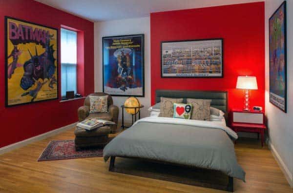 Cozy bedroom with a bold red accent wall, artwork, gray-bedded bed, and a snug reading nook with an armchair