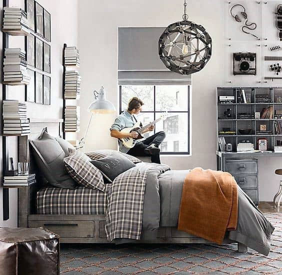 Cozy bedroom with a man playing guitar by the window, surrounded by books and industrial-style decor
