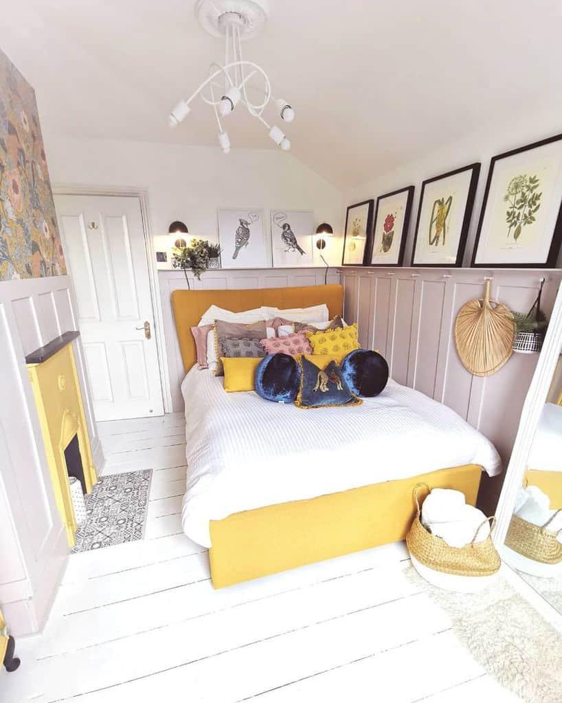 Cozy yellow-themed bedroom with decorative pillows, wall art, and a fireplace; bright and inviting decor