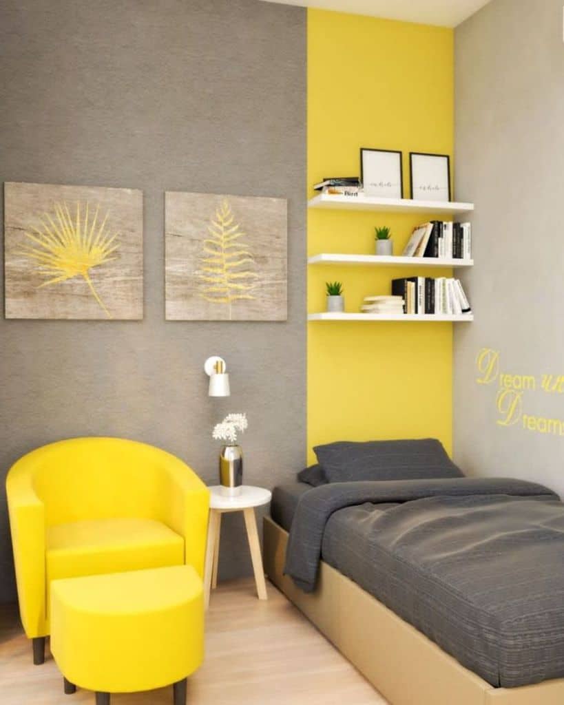 Modern bedroom with a vibrant yellow and gray theme, featuring a cozy bed, chair, artwork, shelves, and decorative pillows