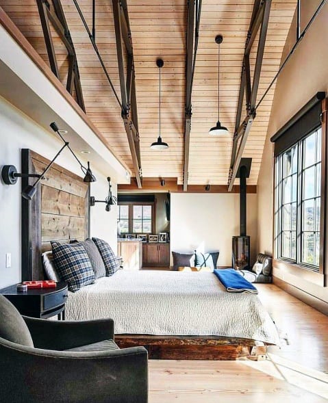 Modern rustic bedroom with exposed wood ceiling beams, pendant lighting, and cozy furnishings.