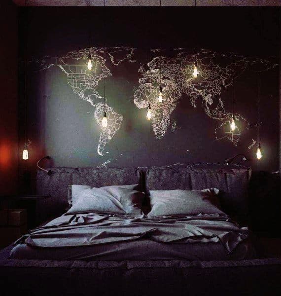 Dark bedroom with glowing world map wall art and hanging Edison bulb lighting.