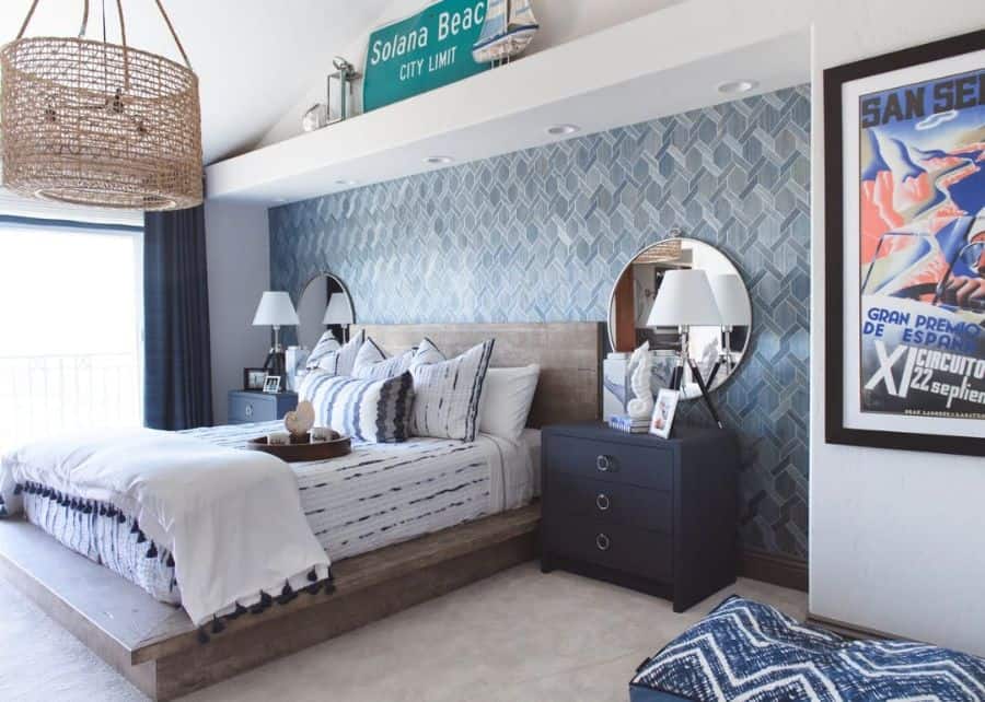 Coastal bedroom with blue accent wall, wood bed, round mirrors, and cozy decor.