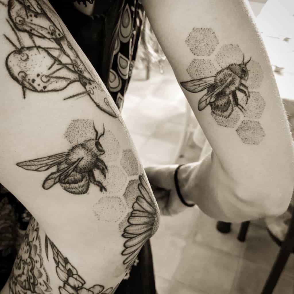Matching bee sister tattoos featuring detailed bees with honeycomb patterns in a black and grey dotwork style
